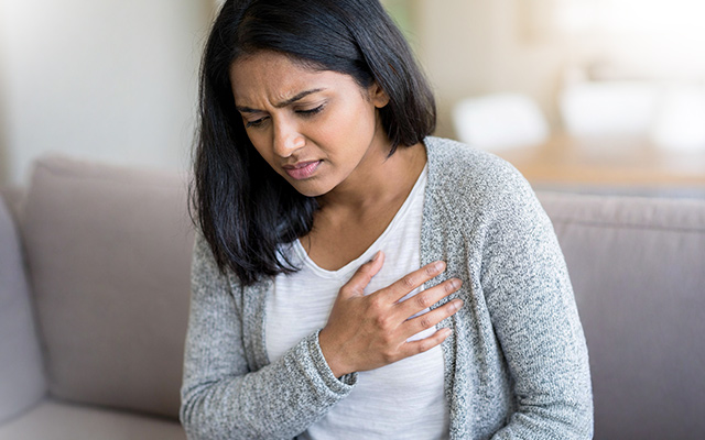 A woman holding her chest in pain, indicating potential heart trouble or discomfort. The image emphasizes the importance of recognizing heart-related symptoms early.